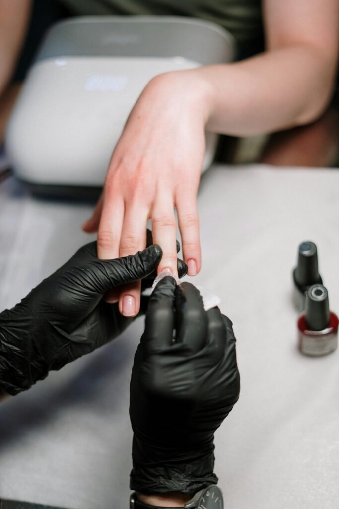 Manicurista profesional realizando servicio de uñas con guantes negros
