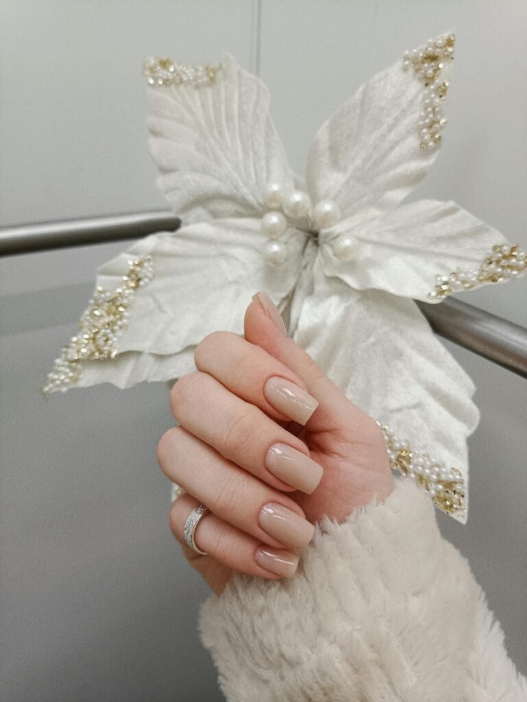 Uñas recien manicuradas frente a flor blanca